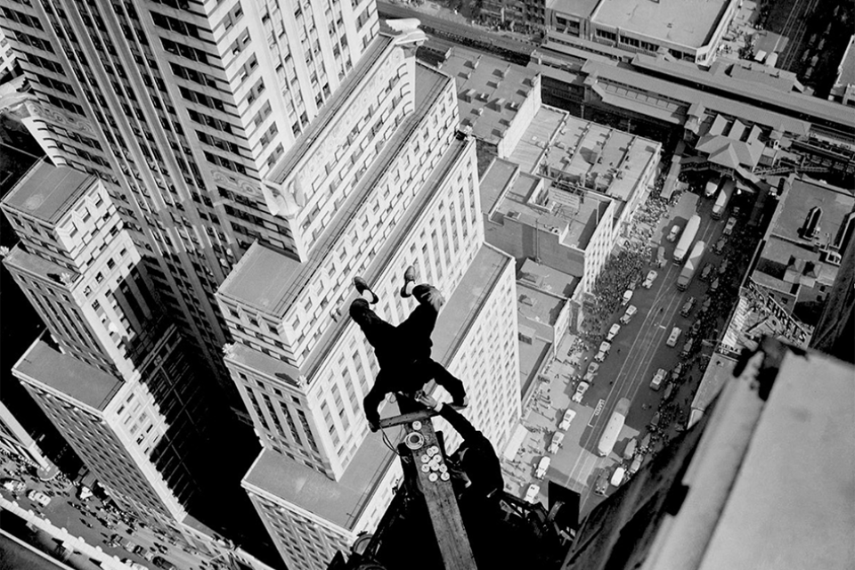 Alvin 'Shipwreck' Kelly, a professional flagpole sitter, eating dunked donuts whilst handstanding on the Chanin Building. Kelly ate 13 donuts during the stunt. (1939), 200 jaar kijken