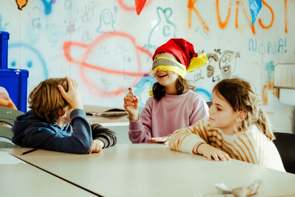 wijzende kinderen tijdens workshop met kleurrijke achtergrond